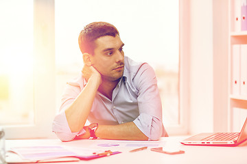 Image showing bored businessman with laptop and papers at office