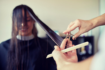 Image showing happy woman with stylist cutting hair at salon