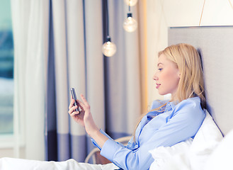 Image showing happy businesswoman with smartphone in hotel room