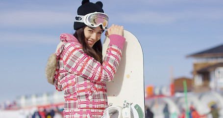 Image showing Cute asian female snowboarder relaxing on slope