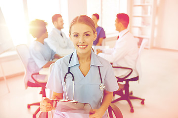 Image showing happy doctor with clipboard over group of medics