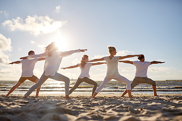 Image showing group of people making yoga exercises on beach