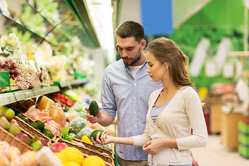 Image showing happy couple buying avocado at grocery store