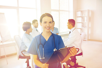 Image showing happy doctor with clipboard over group of medics