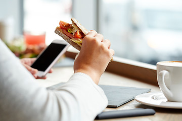 Image showing woman with smartphone and sandwich at restaurant