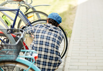 Image showing man fastening bicycle lock on street parking