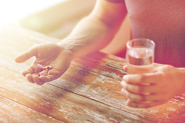 Image showing close up of male hands holding pills and water