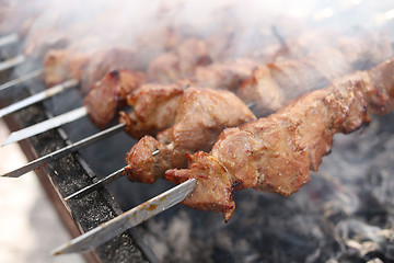 Image showing Grilling marinated shashlik on a grill. Shish kebab popular in Eastern, Central Europe and other places. 