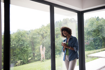 Image showing African American woman drinking coffee looking out the window