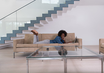 Image showing African American woman using laptop on sofa