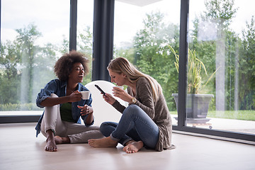 Image showing multiethnic women sit on the floor and drinking coffee