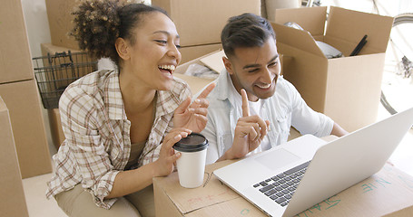 Image showing Happy mixed race couple discuss while using laptop