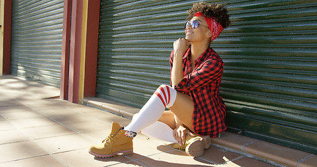 Image showing Gorgeous african american girl sitting next to fence