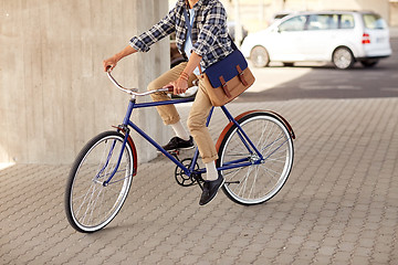 Image showing young hipster man with bag riding fixed gear bike