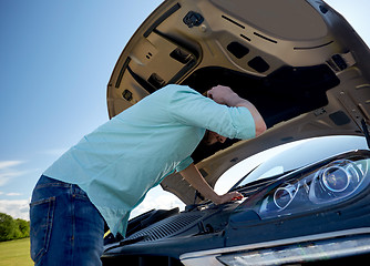 Image showing man with open hood of broken car at countryside