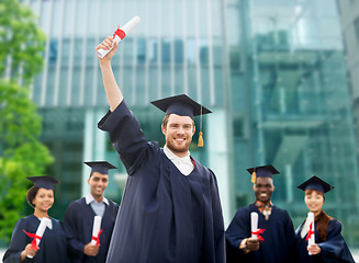 Image showing happy students in mortar boards with diplomas