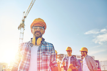 Image showing group of smiling builders in hardhats outdoors