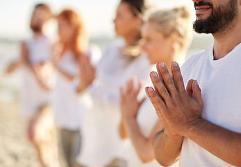Image showing group of people making yoga or meditating on beach