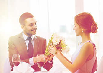 Image showing smiling man giving flower bouquet at restaurant