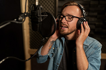 Image showing man with headphones singing at recording studio