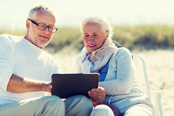 Image showing happy senior couple with tablet pc on summer beach