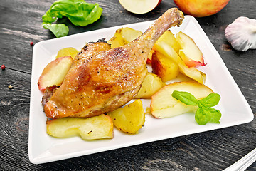 Image showing Duck leg with apple and potatoes in plate on board