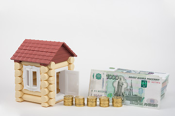 Image showing At toy house opened the door, the door are stacks of coins and a stack of banknotes