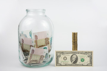 Image showing Close to three-liter jar filled with money is a stack of coins next to it is a banknote of ten dollars