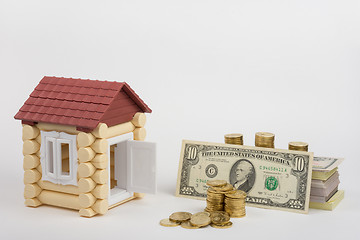 Image showing Toy house near the money is to purchase a pack of bills and a stack of coins