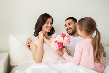 Image showing happy girl giving flowers to mother in bed at home