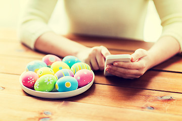 Image showing close up of hands with easter eggs and smartphone