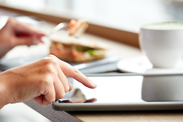 Image showing woman with tablet pc and panini sandwich at cafe