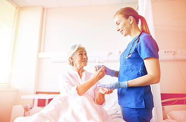 Image showing nurse giving medicine to senior woman at hospital