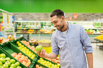 Image showing happy man buying green apples at grocery store