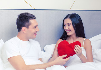 Image showing smiling couple in bed with red heart shape pillow