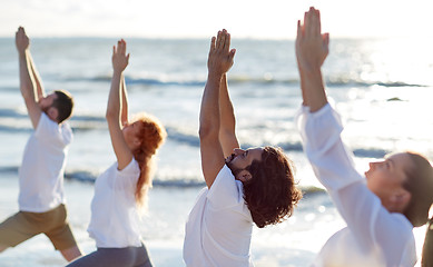 Image showing group of people making yoga exercises on beach