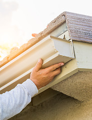 Image showing Worker Attaching Aluminum Rain Gutter to Fascia of House.