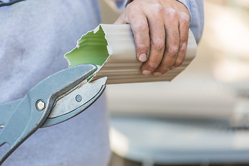 Image showing Worker Cutting Aluminum Rain Gutter With Heavy Shears