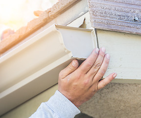 Image showing Worker Attaching Aluminum Rain Gutter to Fascia of House.