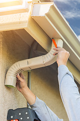 Image showing Worker Attaching Aluminum Rain Gutter and Down Spout to Fascia o