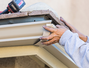 Image showing Worker Attaching Aluminum Rain Gutter to Fascia of House.