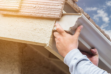 Image showing Worker Attaching Aluminum Rain Gutter to Fascia of House.