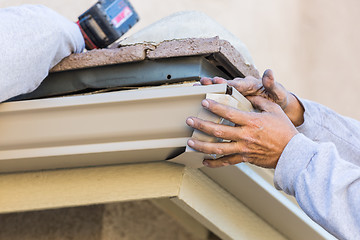 Image showing Worker Attaching Aluminum Rain Gutter to Fascia of House.