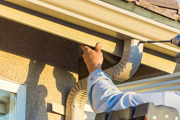 Image showing Worker Attaching Aluminum Rain Gutter and Down Spout to Fascia o