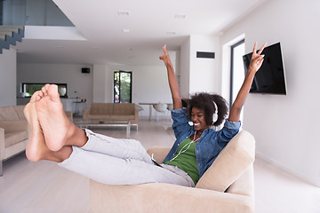 Image showing African american woman at home in chair with tablet and head pho