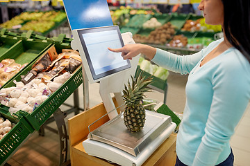 Image showing woman weighing pineapple on scale at grocery store