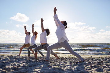 Image showing group of people making yoga exercises on beach