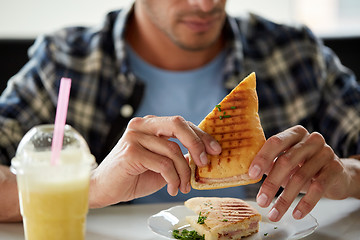Image showing close up of man eating sandwich at cafe for lunch