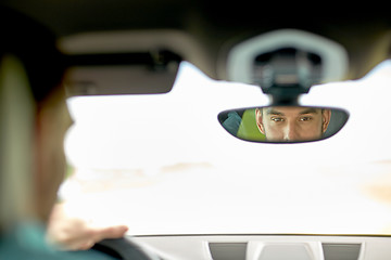 Image showing rearview mirror reflection of man driving car