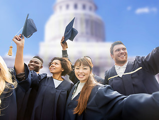 Image showing happy students or bachelors waving mortar boards